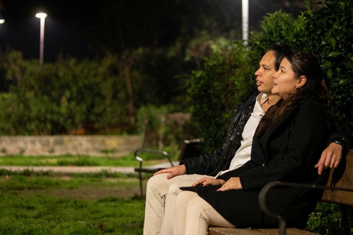 Los novios sentados en un banco del parque, de noche, con una farola al fondo